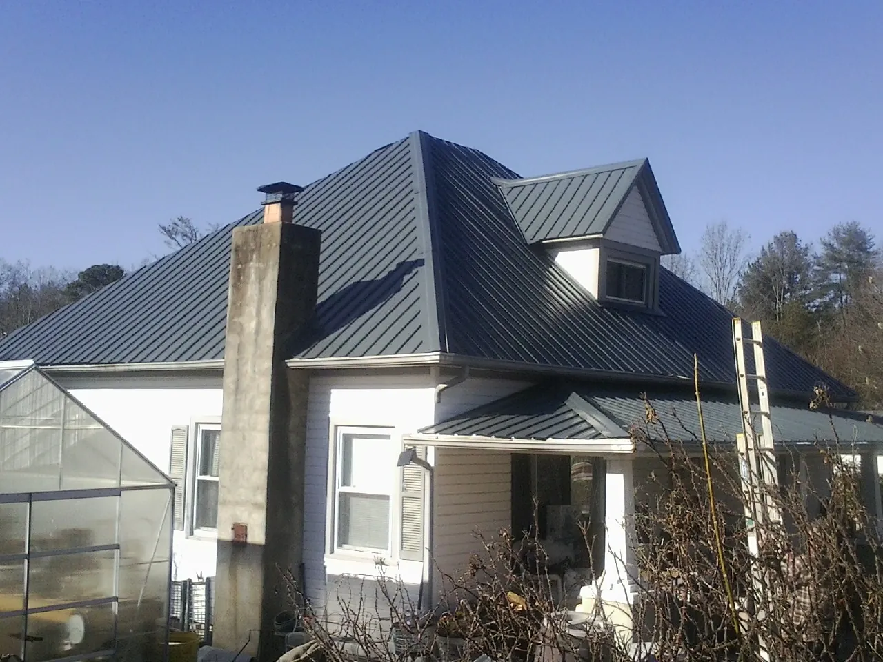 Dark blue standing seam metal roof on a white farmhouse with dormer — Slate & Tile Roof Repair by Roofing Brothers in Bradfordsville