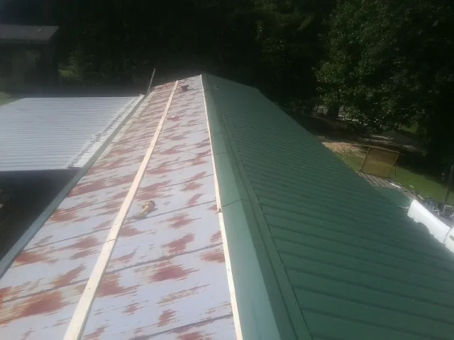 Old rusted panels beside newly installed green metal roofing — Wind Damage Roof Repair by Roofing Brothers in Bradfordsville