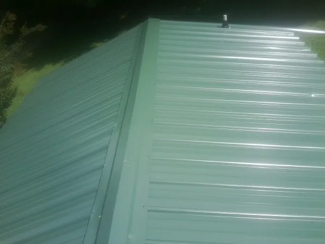 New green metal panels meeting at the ridge of a roof — Flat Roof Repair work by our crew in Bradfordsville