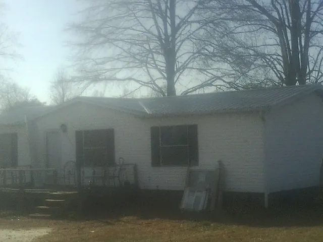 New metal roof on a white painted brick home on a foggy morning in Bradfordsville