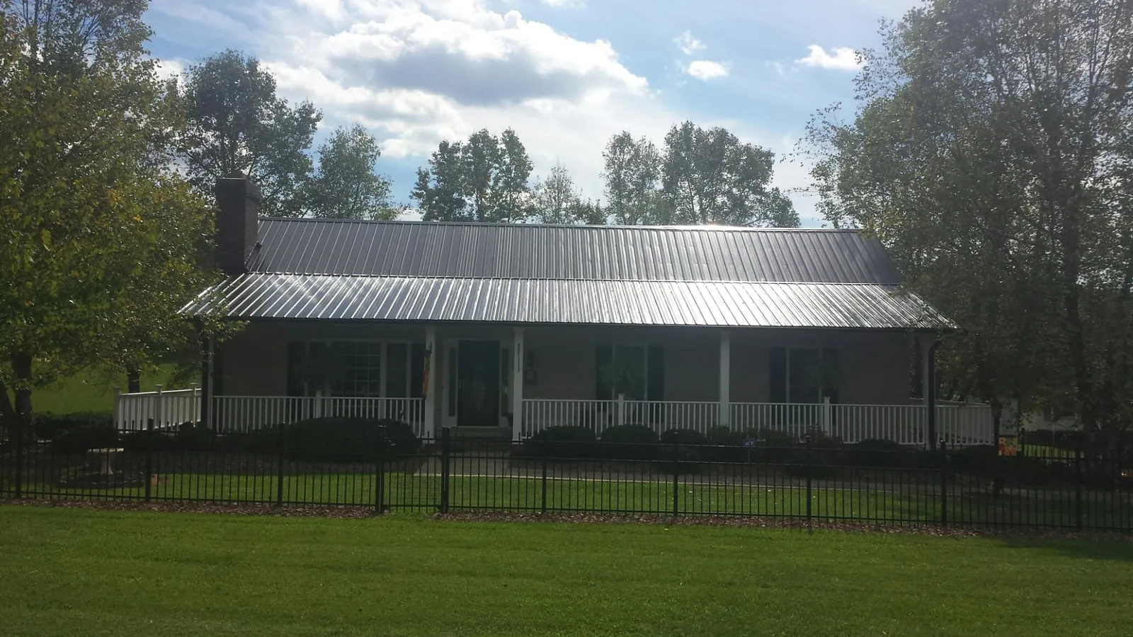 Gray metal roof on a brick ranch with a full width front porch — Gutter Guard Installation work by our crew in Bradfordsville