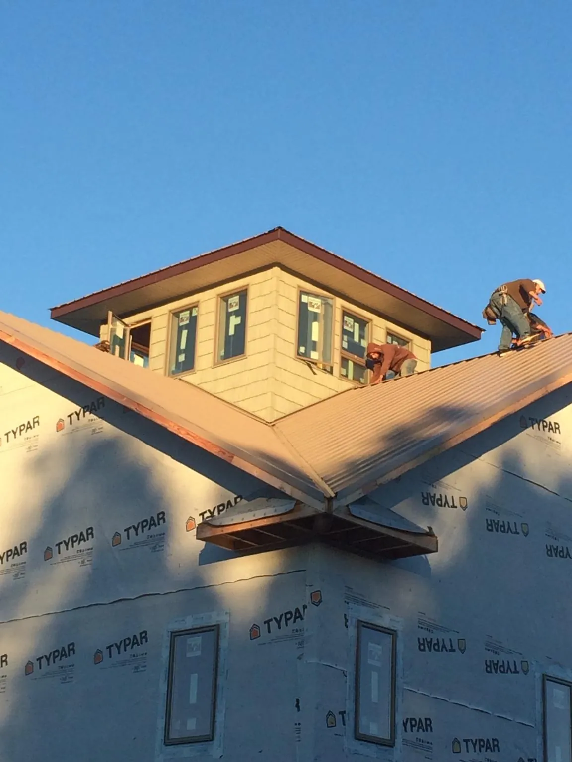 Roofers working around a rooftop cupola on a new metal roof at sunset — Roof Waterproofing in Bradfordsville by Roofing Brothers